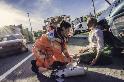 Female doctor providing first aid to woman injured in car accident.